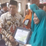 Bupati Fadeli memberikan piagam pada CJH termuda. 