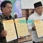 Prof Dr KH Asep Saifuddin Chalim, MA dan Muhammad Syarif Bando menunjukkan MoU Amanatul Ummah dan Perpusnas di Masjid Kampus KH Abdul Chalim Kampus IKHAC Pacet Mojokerto, Rabu (19/7/2023). Foto: M Mas