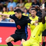 Penyerang Barcelona Robert Lewandowski (hitam) berebut bola dengan bek Villareal Logan Costa selama pertandingan Liga Spanyol antara Villarreal vs Barcelona di Stadion La Ceramica di Vilarreal pada 22 September 2024. (Foto oleh JOSE JORDAN / AFP)(AFP/JOSE JORDAN)