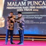 Arif Afandi ketika menerima penghargaan dari Ketua PWI Jatim Lutfil Hakim. Foto: dok pribadi