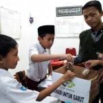 Seorang pelajar menyalurkan bantuan untuk korban banjir bandang Garut, Jabar melalui Lazisnu Jombang, Senin (26/9). foto: ROMZA/ BANGSAONLINE