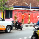 Tiga orang berseragam PNS tampak mengecat tembok yang sebelumnya berisi mural bernada kritik dengan cat warna merah.