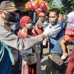 Polsek Duduksampeyan saat bagi-bagi masker kepada pengunjung dan pedagang pasar. (foto: ist)