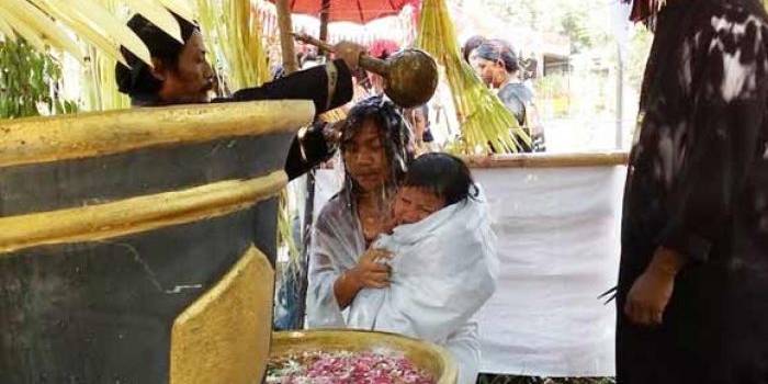 DIRUWAT: Seorang ibu muda bersama anak balitanya mendapat siraman air tujuh sumber di Pendopo Agung Trowulan, kemarin. foto: gunadhi/BANGSAONLINE