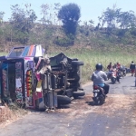 Bus yang terguling sedang disaksikan warga.