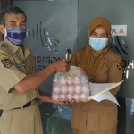 Petugas saat akan menyerahkan bantuan sembako kepada warga yang sedang menjalani isolasi mandiri. (foto: ist)