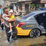 Sejumlah anggota polisi menggendong beberapa anak sekolah dari rumah mereka. 