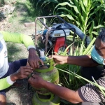 Paeran Al Sugeng Ariadi, Ketua Kelompok Tani Makmur Dusun Tegalsari, Desa Blimbing (kanan) dengan salah seorang petani saat memasang Tabung Gas Elpiji. (foto: MUJI HARJITA/ BANGSAONLINE)