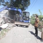 BONGKAR: Bupati Ahmad Muhdlor (kiri) menyaksikan pembongkaran bangunan untuk Frontage Road di Desa Gedangan, Senin (27/7/2021).