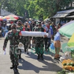 Anggota TNI dan Polri membopong pocong sambil menyosialiasasikan bahaya Covid-19 di Pasar Legi Jombang. foto: AAN AMRULLOH/ BANGSAONLINE