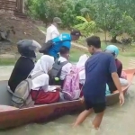 Warga di Kecamatan Balongpanggang saat mengantarkan siswa SD berangkat sekolah dengan perahu dampak desa terendam luapan Kali Lamong. foto: SYUHUD/ BANGSAONLINE