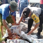 Petugas dibantu warga saat melihat kondisi jenazah korban.