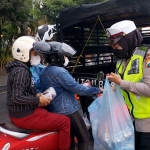 Personel Satlantas Polres Batu saat membagi-bagikan takjil kepada pengendara.