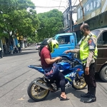 Petugas Satlantas Polres Gresik saat menilang pengendara motor yang menggunakan knalpot brong. Foto: SYUHUD/BANGSAONLINE