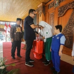 Pj Wali Kota Mojokerto didampingi Kepala Disdikbud saat memberikan bantuan perlengkapan sekolah kepada pelajar.