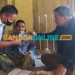 Direktur Rehabilitasi Sosial Lanjut Usia, Supomo, saat memakaikan baju untuk Budeli, kakek penderita hernia puluhan tahun di Sampang. Foto: MUTAMMIM/BANGSAONLINE