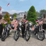 Anggota Polres Gresik memasang bendera merah putih di kendaraan dinas. foto: SYUHUD/BANGSAONLINE.com