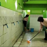 Tampak dua polwan sedang membersihkan toilet dan area tempat wudlu masjid.