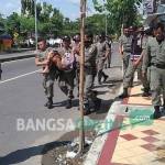 Satpol PP terpaksa menggendong gelandangan yang terjaring razia karena enggan dipulangkan. foto: SUWANDI/ BANGSAONLINE