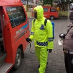 Petugas Satlantas Polres Gresik saat melakukan penyemprotan disinfektan di Parkiran Ziarah Makam Sunan Maulana Malik Ibrahim atau Sunan Gresik. (foto: ist)