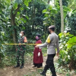 Petugas memasang garis polisi di lokasi penemuan mayat.