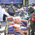 Wali Kota Kediri Abdullah Abu Bakar, saat membantu mendorong becak yang akan menyalurkan bantun dibantu aparat TNI dan Polri. 