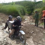 Tampak petugas harus mendorong motor saat melintasi jalanan berlumpur. foto: eki/bangsaonline