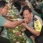 SALING SUAP: Anggota TNI dari Kodim 0809 Kediri tampak menyuapi anggota Polres Kediri Kota. foto: ARIF KURNIAWAN/ BANGSAONLINE