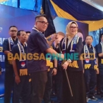 Ketua DPW Nasdem Jatim Lita Mahfud Arifin (kanan) menyerahkan bendera pataka kepada Ketua DPD Nasdem Gresik Jiddan usai dikukuhkan. FOTO: Syuhud/BANGSAONLINE