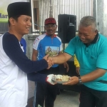 Plt. Bupati Trenggalek Moh. Nur Arifin (kiri) saat menyerahkan potongan tumpeng pada Kepala Kelurahan Kelutan Kec. Trenggalek. foto: HERMAN S/ BANGSAONLINE