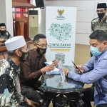 Wali Kota Kediri, Abdullah Abu Bakar (duduk kanan), saat didampingi pengurus Baznas Kota Kediri saat menyaluran zakat dengan cara scan QRIS. Foto: Ist