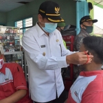 Bupati Pungkasiadi saat memasangkan masker kepada warga. (foto: ist).