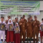 Guru dan siswa terdampak banjir saat foto bersama Kepala Disdikbud Sidoarjo, Tirto Adi, ketika menerima bantuan sepatu boots. Foto: Ist
