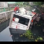 Sopir dan kernetnya gotong royong mengeluarkan paket dari dalam boks.