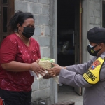 Bhabinkambtimas membagikan daging kurban secara door to door menggunakan besek.