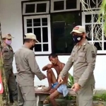 Petugas Satpol PP saat berupaya mengamankan ODGJ yang berkeliaran di sebuah rumah makan.