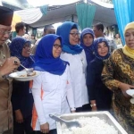 Menteri Sosial, Khofifah Indar Parawansa ketika mengajak pejabat dan masyarakat mencicipi rasa rastra yang dibagikan.