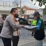 Kapolresta Banyuwangi AKBP Nasrun Pasaribu menyerahkan kotak nasi kepada penjual koran. (foto: ist)