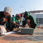 Para Bonek sedang sibuk mengecat paving sekitar GBT.