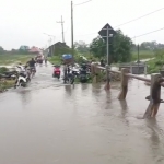 Warga sedang mengevakuasi motornya yang terendam banjir.