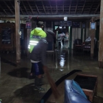 Anggota kepolisian ikut membantu bersih-bersih lumpur bekas banjir bandang.