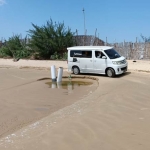 Pengendara yang lalu lalang di Pantai Lombang melintasi pipa pembuangan limbah tambak udang.