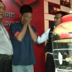 Anggota mendampinggi tersangka dan burung barang bukti. foto: rusmiyanto/BANGSAONLINE