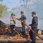 Petugas Damkar Bangkalan saat melakukan pembasahan terhadap kandang ayam yang terbakar.