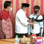 Plt Bupati Nganjuk, Marhaen Jumadi, saat menyerahkan secara simbolis tongkat dan sembako kepada penyandang tunanetra. Foto: BAMBANG/ BANGSAONLINE