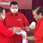 Ketua DPC PDIP Kabupaten Kediri, Murdi Hantoro (kiri) dan Sekretaris DPC PDIP Kabupaten Kediri, Dodi Purwanto (tengah) saat menyerahkan secara simbolis kaos dan makser bergambar Dhito, kepada salah satu pengurus PAC PDIP Kecamatan Pagu, Kediri, Sabtu (19/9/2020). foto: Muji Harjita/ bangsaonline.com.