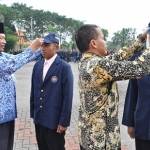 Bupati, Sambari HR saat menyematkan topi KKN mahasiswa Unesa. foto: SYUHUD/ BANGSAONLINE