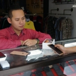 Sandy Dolorosa Hartono saat melayani pembeli di konter handphone miliknya. foto: RONY S/ BANGSAONLINE
