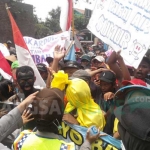 Seorang peserta aksi dengan kostum pocong terjebak rekannya ketika aksi sempat memanas. Aksi di depan Pemkab Mojokerto ini mendapat penjagaan ketat dari polisi. foto: YUDI EP/ BANGSAONLINE