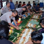 Kapolresta Sidoarjo beserta jajaran tampak guyub bersama para awak media, mengambil makanan yang dibungkus dan diberi alas daun pisang.